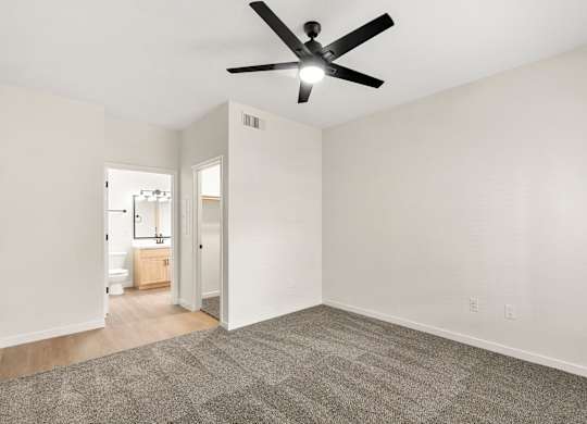 A room with a ceiling fan and carpeted floor.