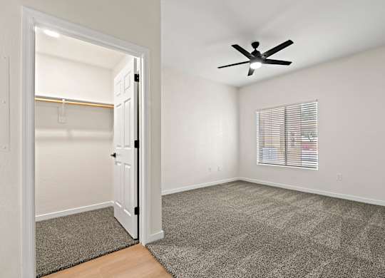 A room with a ceiling fan and a door leading to another room.