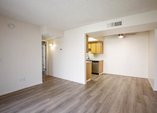 A kitchen area with a sink and cabinets is visible through an open doorway.