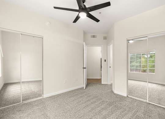 A room with a ceiling fan and carpeted floor.