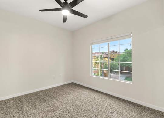 A room with a ceiling fan and a window showing an outdoor view.