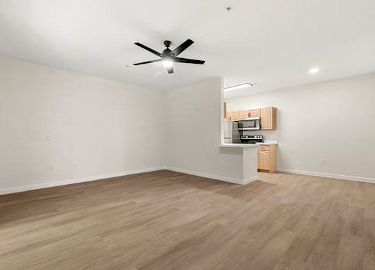 A room with a ceiling fan and a small kitchenette.