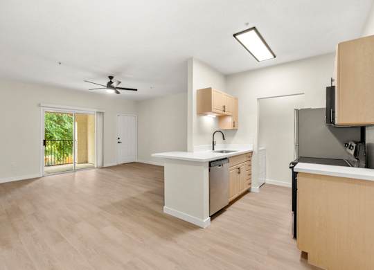 A kitchen with a fan on the ceiling and a dishwasher in the sink.