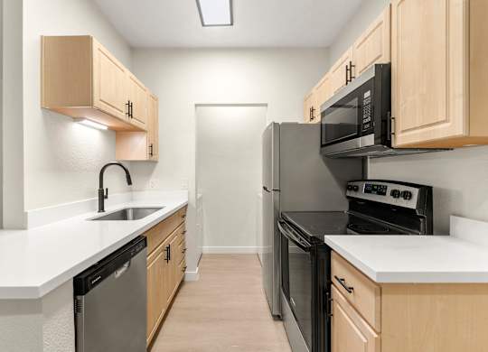 A kitchen with wooden cabinets and black appliances.
