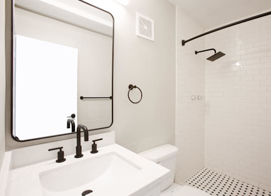A modern white bathroom with a sink, mirror, and tiled shower