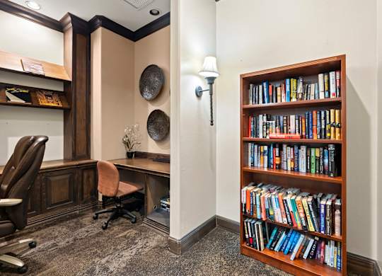 A room with a bookshelf filled with books and a desk with a chair.