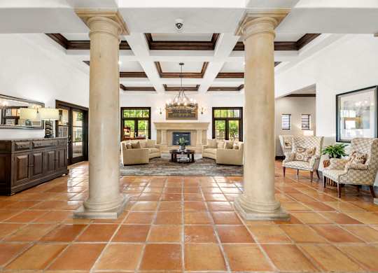 A spacious living room with a fireplace and a chandelier.