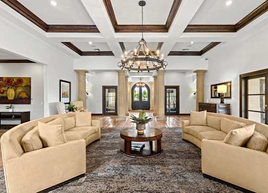 A large, elegant living room with a chandelier and two couches.
