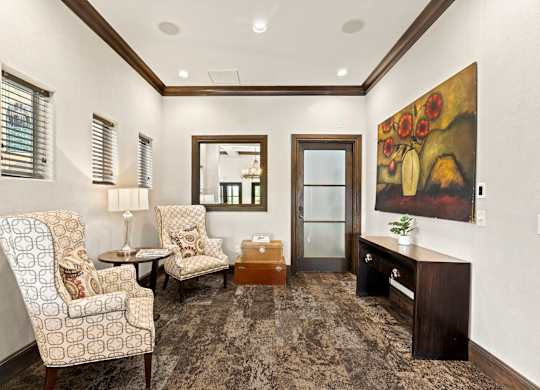 A living room with a patterned carpet and a painting on the wall.