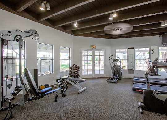 A gym with a variety of equipment including treadmills, weights, and exercise machines.