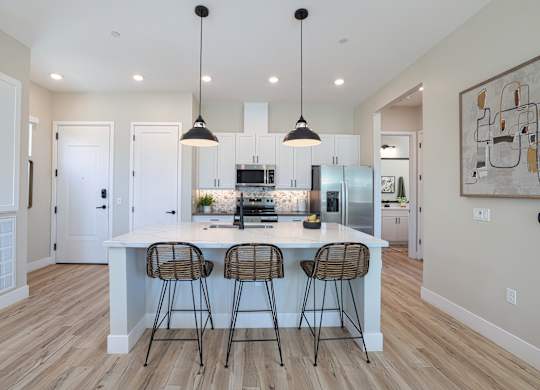 A kitchen with a white island and bar stools.