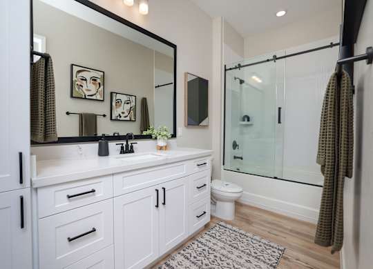 A bathroom with a white cabinet and a mirror above the sink.