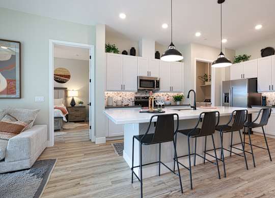 A kitchen with a white island and black barstools.