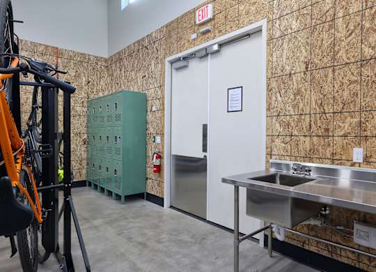 A room with a sink and a door with an exit sign above it.