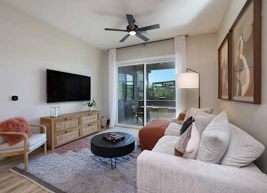 A living room with a white couch and a flat screen TV mounted on the wall.