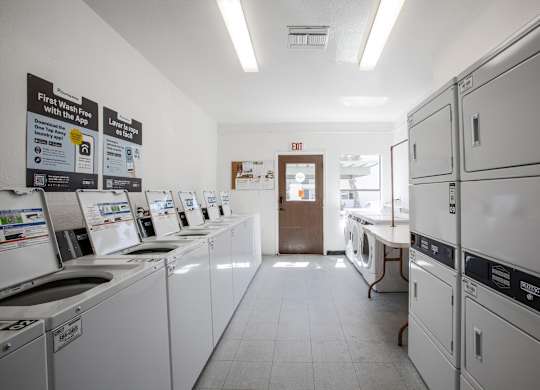 A laundromat with washers and dryers lined up.
