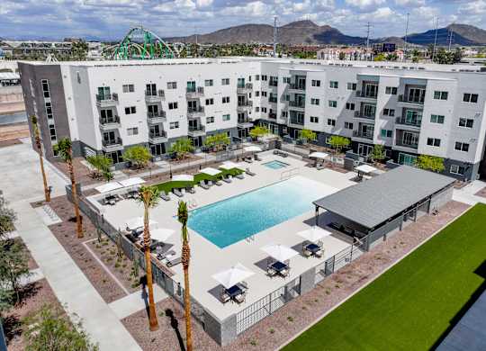 A large white apartment complex with a pool in the middle.