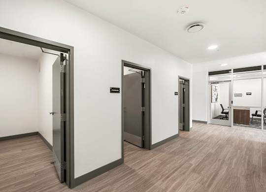 A room with a white wall and a wooden floor with a door.
