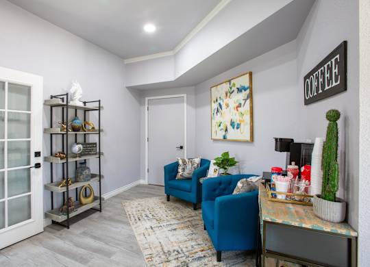 A living room with a blue couch and a coffee sign on the wall.