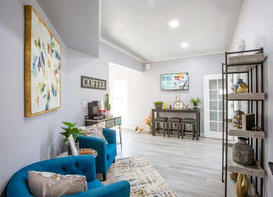 A living room with a blue couch and a coffee sign on the wall.