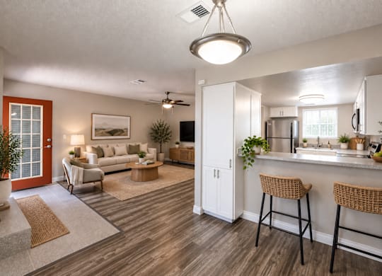 A living room with a bar area and a kitchen in the background.