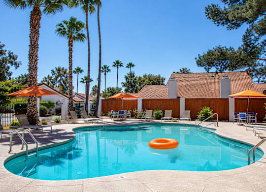 A pool with a blue tinted water and a floating orange ring in the middle.