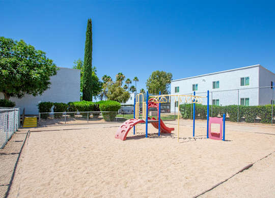 A playground with a red slide and a blue climbing frame.