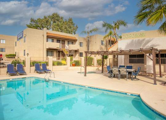 A pool area with chairs and a building in the background.