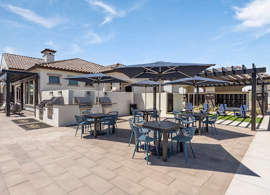 A patio with tables and chairs is shaded by umbrellas.