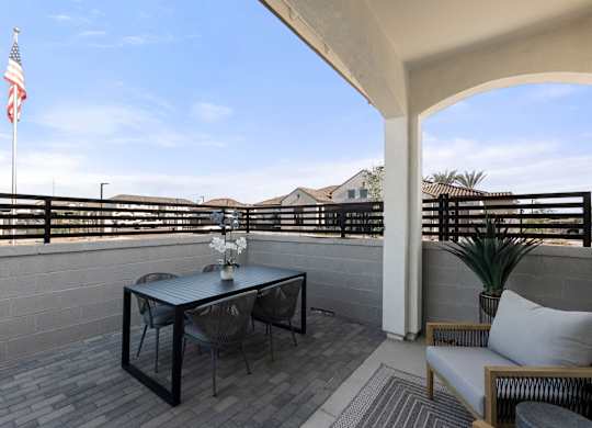 A balcony with a table, chairs, and an American flag.