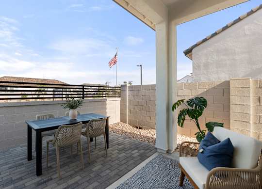 A patio with a table, chairs, and a couch with a pillow on it.