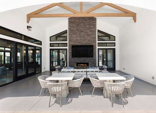 A modern dining room with a stone fireplace and white furniture.