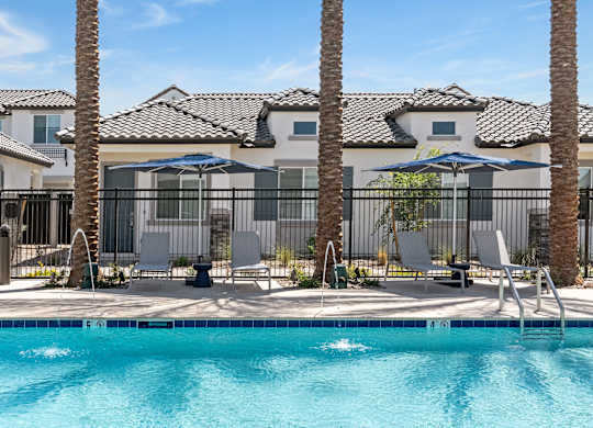 A pool surrounded by palm trees and lounge chairs.