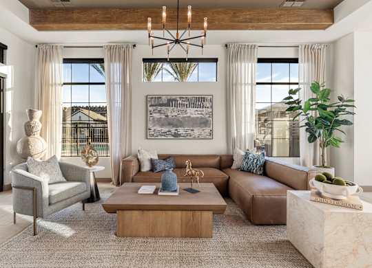 A living room with a large couch, a coffee table, and a chandelier.