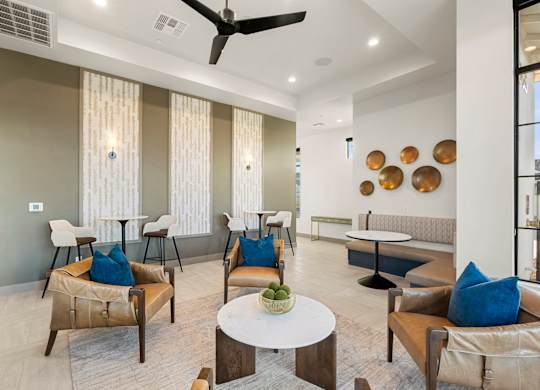A living room with a fan, chairs, and a table.