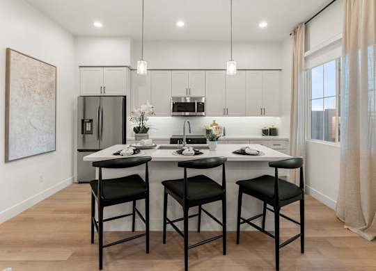 A modern kitchen with a dining table and chairs.
