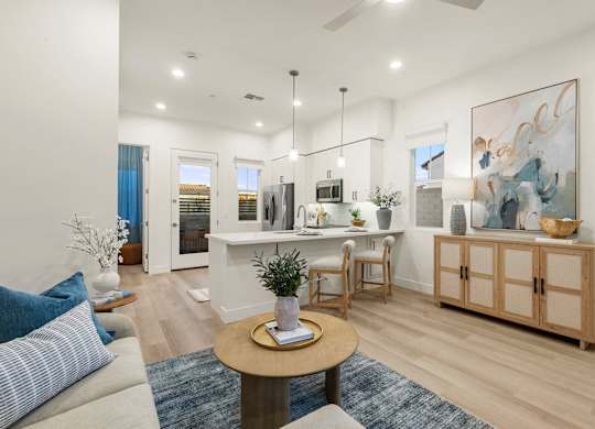 A living room with a white sofa, a wooden coffee table, and a painting on the wall.