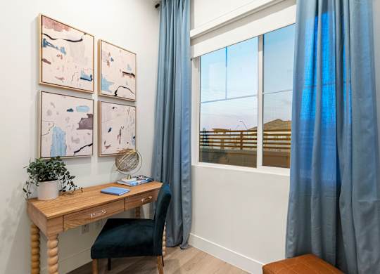 A room with a desk, chair, and pictures on the wall.