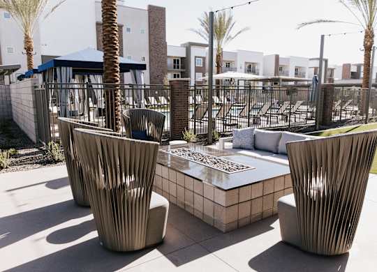 Two large chairs sit on a patio with a table between them.