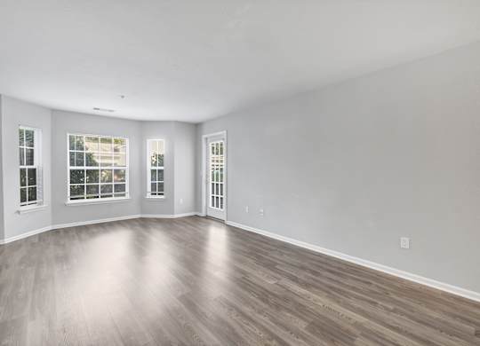 A spacious room with wooden flooring and three windows. at Ardenwood Apartments, North Haven