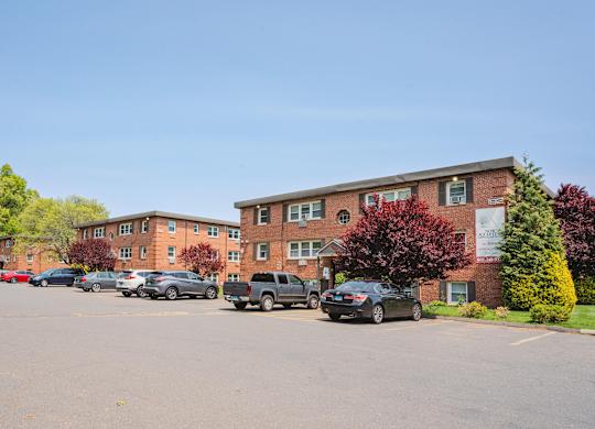 a parking lot with cars in front of an apartment building at Springwood Gardens, Connecticut, 06053