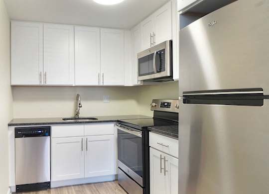 an empty kitchen with white cabinets and stainless steel appliances at The Packard, Connecticut, 06119