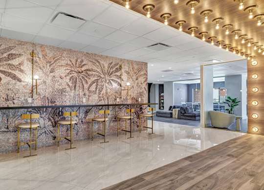 a lobby with a bar with chairs and a wall mural of palm trees at Up House, Farmington, CT, 06032