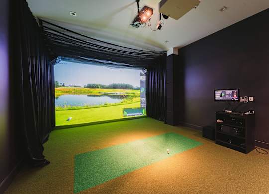 a room with a view of a golf course and a projector screen on the wall at Up House, Farmington