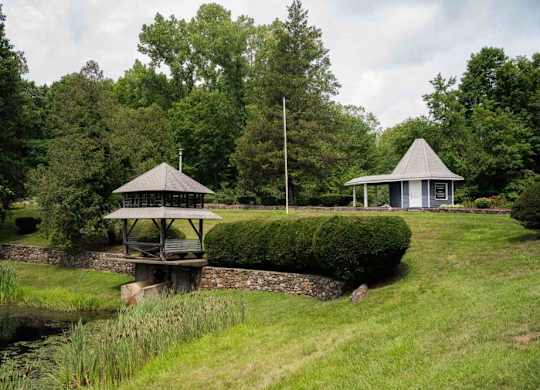 a gazebo and a pavilion in a park next to a river at Woodbury Knoll, Woodbury, 06798