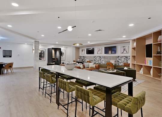 A modern kitchen with a long white island and green barstools.