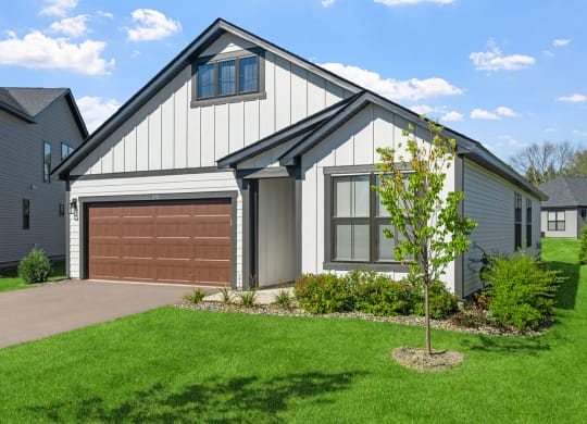 a home with a brown garage door in front of a green lawn