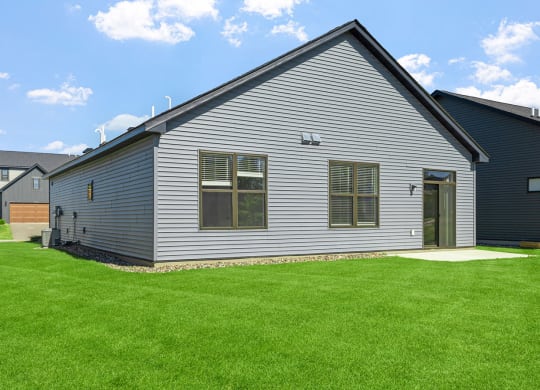 a gray house with a green lawn in front of it