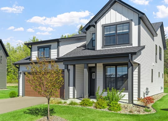 a gray house with a garage and a lawn