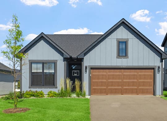 a home with a brown garage door in front of a green lawn